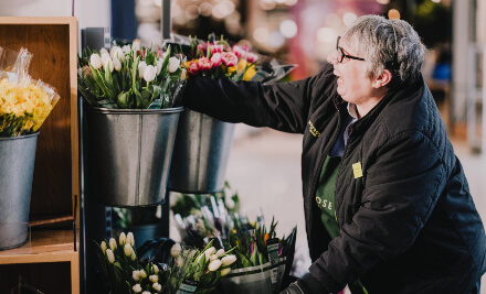 A woman working at Waitrose while arranging some flowers