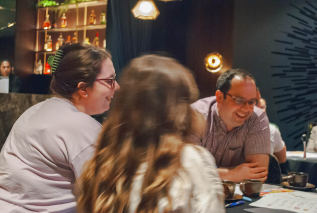 Three colleagues sitting around a table and laughing