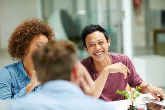Three colleagues laughing around a table
